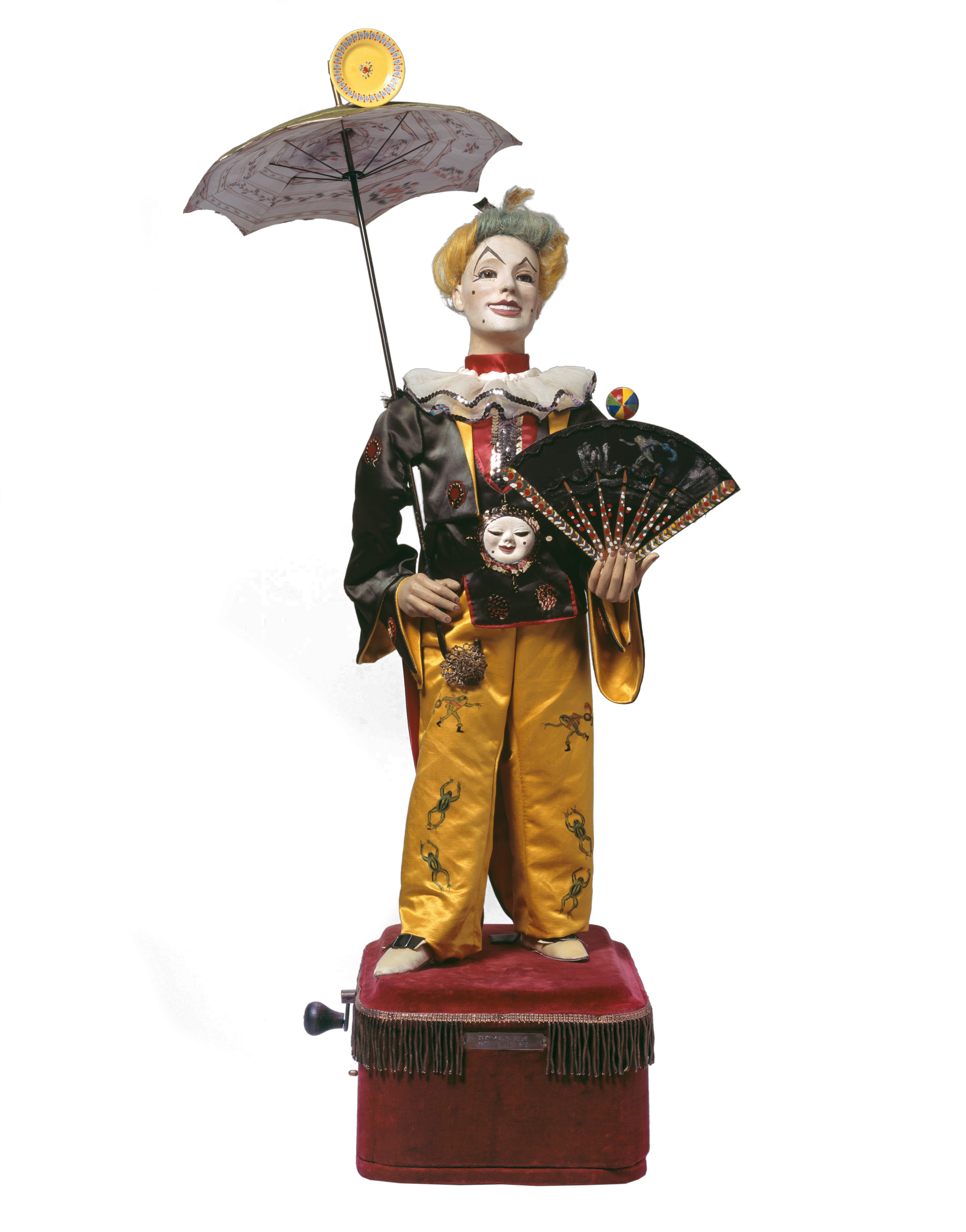 Das Bild zeigt einen Musikautomaten in Form eines Clowns mit einem Fächer in der Hand und einem Schirm in der anderen Hand.