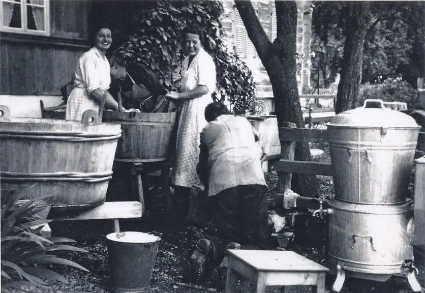 Waschtag um 1930: zwei Frauen waschen vor dem Haus in Waschzubern die Wäsche.