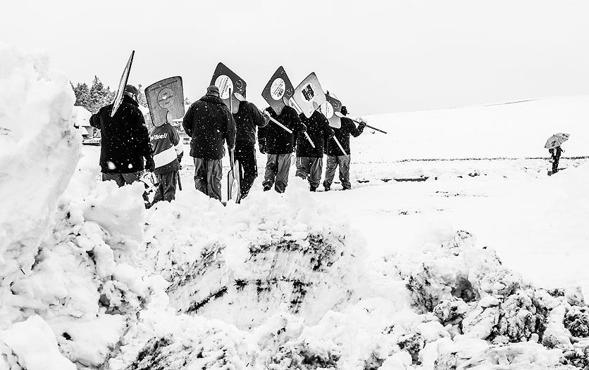 Ein Hornussen-Team schreitet mit ihren Schindeln durch den Schnee.
