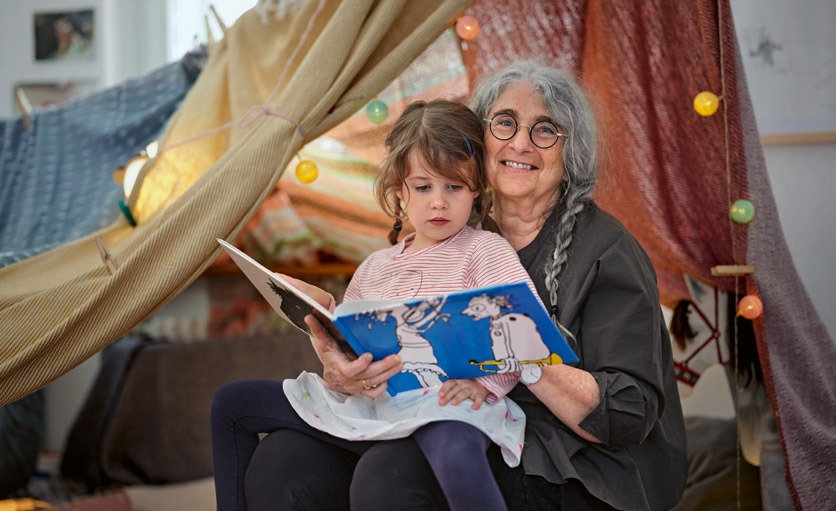 Eine Grossmutter liest ihrer Enkeltochter ein Buch vor.
