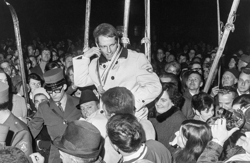 Alois Kälin bei seiner Rückkehr von den Olympischen Winterspielen in Grenoble in Zürich. Er wird durch eine Menschenmenge getragen.
