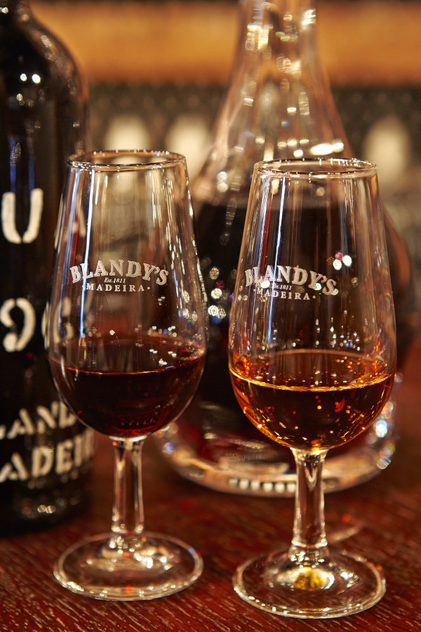 Zwei Gläser Blandys, Madeira-Wein, stehen auf einer Theke.