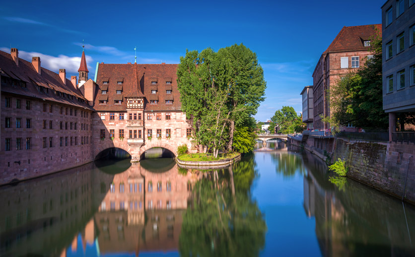 Heilig-Geist-Spital in Nürnberg spiegelt sich in der Pegnitz von der Museumbrücke aus.
