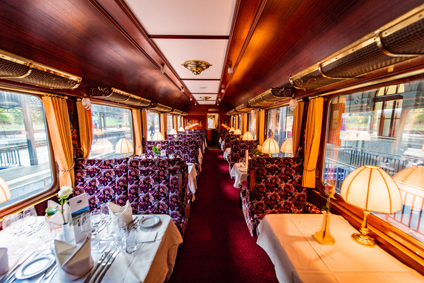 Speisewagen mit Tischen und angenehmer Beleuchtung im Suisse Train Bleu.