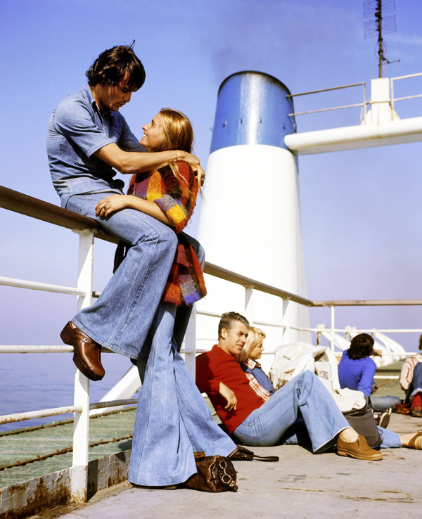 Junge Paare in Schlaghosen auf einem Schiff in den 1970er Jahren.