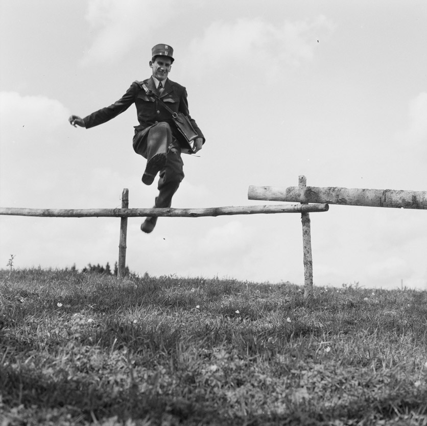 Der schnellste Briefträger der Schweiz springt über einen Zaun. (Schweizermeister im Gehen)
