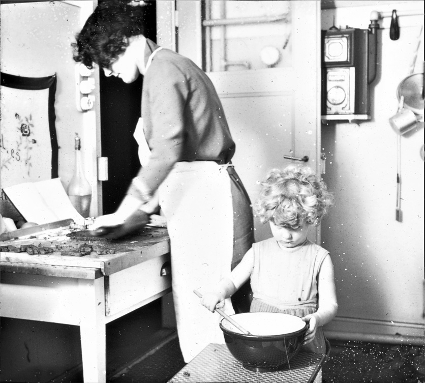 Anno 1930: Guetzli backen mit der Mutter. Ein kleiner Junge mit blonden Locken rührt in einer Teigschüssel. 