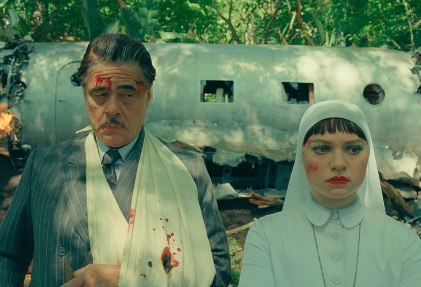 Benicio Del Torro und Mia Threapleaton stehen verwundet vor einem Flugzeugwrack.