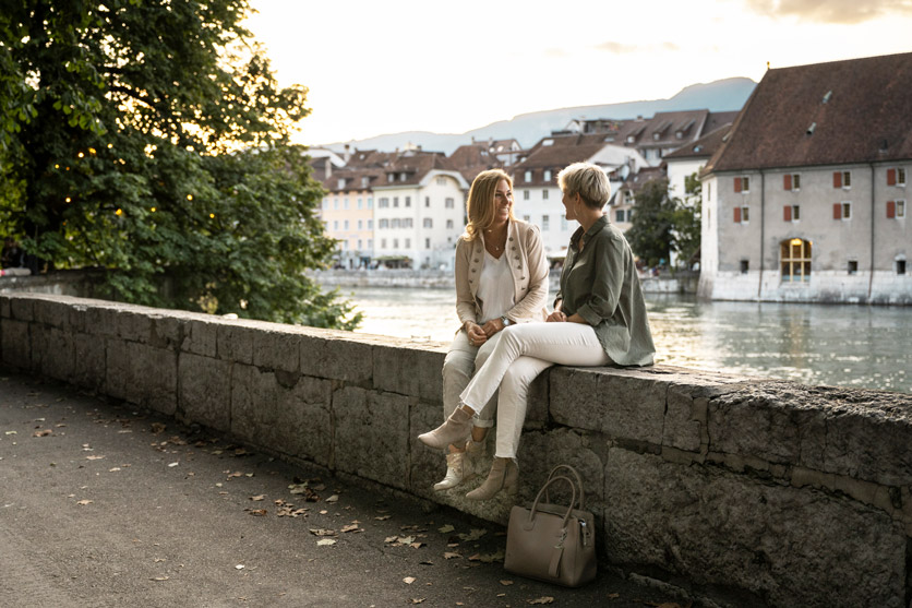 Zwei Frauen sitzen in Solothurn auf einer Mauer an der Aare