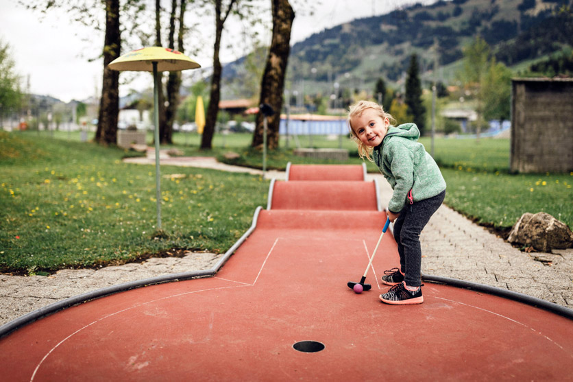 Mädchen spielt Minigolf im Frutigresort Camping