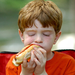 Ein rothaariger Junge isst ein Hotdog