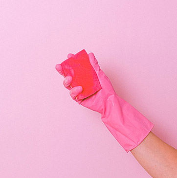 Hand mit pinkem Gummihandschuh und pinkem Schwamm